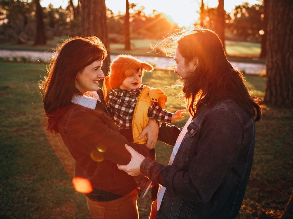 Padres jugando con su hijo en un parque soleado