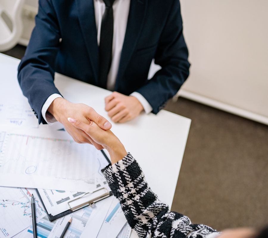 Dos profesionales dándose la mano sobre un escritorio